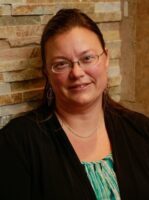 A headshot of a Caucasian woman with straight, brown hair and brown eyes.