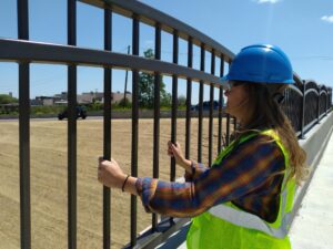 Employee grasps bridge rails in contemplative joy.