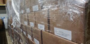 Close-up of cardboard boxes labeled "Vikre Distillery" and wrapped together in clear plastic film.