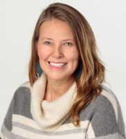 A headshot of a Caucasian woman with wavy, light brown hair and blue eyes.