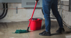 an adult mopping a large puddle from a concrete floor