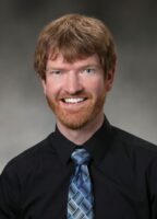 A headshot of a caucasian man with red hair, a red beard, and blue eyes.