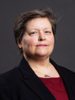 A headshot of a Caucasian woman with short, dark brown hair.
