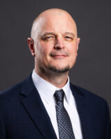 an image of a Caucasian man with shaved head and trimmed goatee