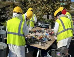 people in personal protective equipment sorting trash